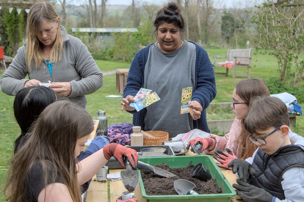 Group of children sat at table, planting seeds